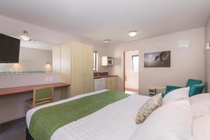 a bedroom with a large bed and a kitchen at Bella Vista Motel New Plymouth in New Plymouth