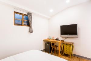 a bedroom with a bed and a desk with a television at CandyFloss 棉花糖民宿 遊高雄 in Kaohsiung