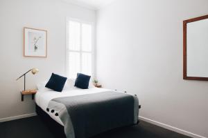 a white bedroom with a bed with blue pillows at Naughtons Hotel in Melbourne