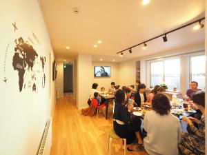 a group of people sitting at tables in a room at Family Tree Guest House in Sapporo