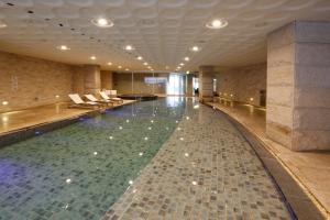 a large swimming pool in a building with chairs at Grand Mercure Ambassador Changwon in Changwon