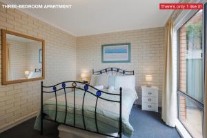 - une chambre avec un lit et un miroir dans l'établissement Panoramic Townhouses by Lisa, à Merimbula