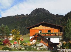 a brown building with a balcony and a mountain at Ferienwohnung Alpklang in Untertauern