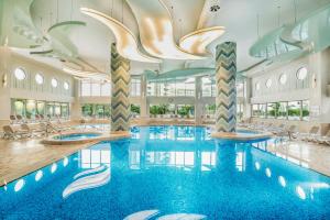 a large swimming pool in a hotel with a chandelier at Titanic Deluxe Lara in Lara