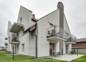 ein weißes Gebäude mit 2 Balkonen und Tischen in der Unterkunft Apartamenty Marina Jastarnia Bis in Jastarnia