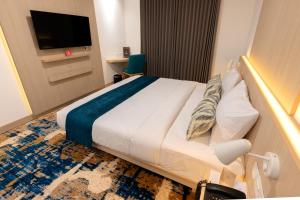 a hotel room with a bed and a tv at Cordia Hotel Yogyakarta - Hotel Dalam Bandara in Glagah