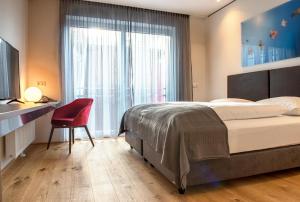 a bedroom with a large bed and a red chair at Hotel Wallern Garni in Wallern an der Trattnach +26 photos