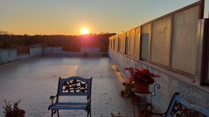 zwei Bänke auf einem Balkon mit Blick auf den Sonnenuntergang im Hintergrund in der Unterkunft Rose Room in Rom