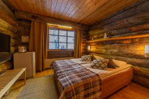 a bedroom with a bed in a log cabin at Kuukkeli Log Houses Teerenpesä in Saariselka