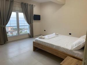 um quarto com uma cama e uma grande janela em Kotarja Apartments em Dhërmi