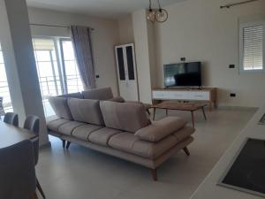 a living room with a couch and a tv at Kotarja Apartments in Dhërmi