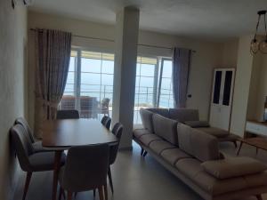 uma sala de estar com um sofá, uma mesa e cadeiras em Kotarja Apartments em Dhërmi