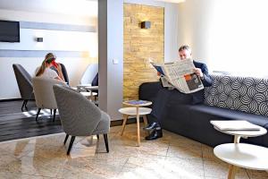 a man sitting on a couch reading a newspaper at Tulip Inn Frankfurt Airport in Neu Isenburg