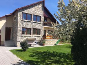 una casa de piedra con un patio verde delante de ella en Kazinczy Apartman, en Balatonalmádi