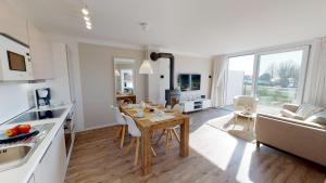 a kitchen and living room with a wooden table and chairs at Beach'n'Sea Wohnung 7 in Grömitz