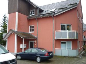 un coche negro estacionado frente a una casa roja en Ferienwohnung Braunlage, en Braunlage