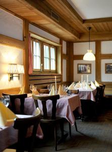 ein Esszimmer mit 2 Tischen, Stühlen und Fenstern in der Unterkunft Hotel-Restaurant zum Gade in Lenk im Simmental