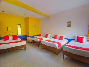 Cette chambre comprend 4 lits avec des draps rouges et blancs. dans l'établissement OYO Hotel Posada Los Faroles,Tabasco, à Villahermosa