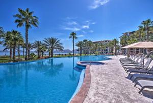 a swimming pool with lounge chairs and palm trees at Colorful Paraiso del Mar Resort Condo with Patio! in La Paz