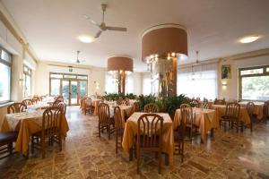 uma sala de jantar com mesas e cadeiras com toalha de mesa amarela em Hotel Kristall em Diano Marina