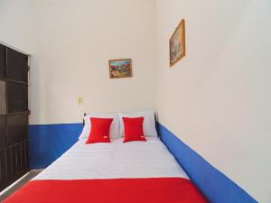 a bed with two red pillows in a room at OYO Hotel Posada Los Faroles,Tabasco in Villahermosa