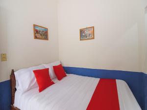 - une chambre avec un lit doté d'oreillers rouges et blancs dans l'établissement OYO Hotel Posada Los Faroles,Tabasco, à Villahermosa