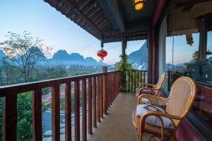 a balcony with chairs and a view of mountains at Yangshuo Mountain Nest Boutique Hotel in Yangshuo