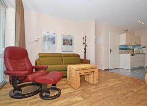 a living room with a red chair and a couch at Ferienanlage Seeblick Unterdeck in Ostseebad Koserow