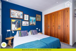 a blue bedroom with a bed and pictures on the wall at Solhabitat Coll de Mar in Calpe