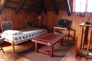 a bedroom with a bed and a table and a tv at Myoli Beach Lodge in Sedgefield