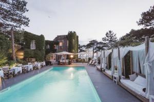 a swimming pool with tables and chairs next to a building at Domaine Saint Clair - Le Donjon in Étretat
