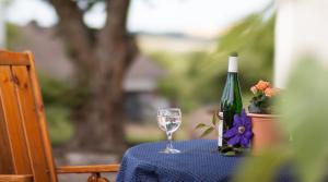 a bottle of wine and a wine glass on a table at Landhaus Heimisch Bed & Breakfast in Geisfeld