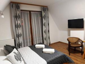 a bedroom with a bed and a chair and a television at Apartamenty Majerczyk in Zakopane