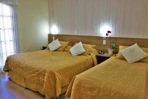 2 camas en una habitación de hotel con 2 camas en Hotel Bologna, en Campos do Jordão