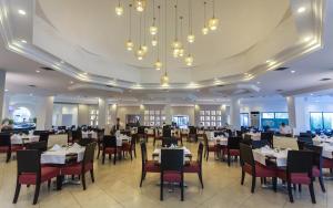 una sala da pranzo con tavoli, sedie e lampadari a braccio di Djerba Aqua Resort a Midoun