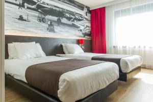 
a hotel room with two beds and a painting on the wall at Bastion Hotel Amsterdam Airport in Hoofddorp
