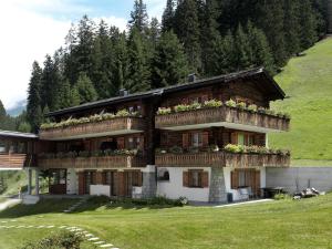 a house with flowers on the balconies on a hill at Hotel Dieschen in Lenzerheide