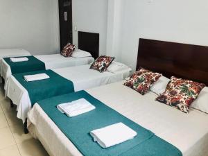 three beds in a room with towels on them at Mais Hotel in Araguaína +26 photos