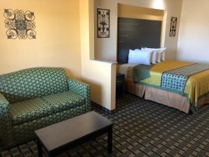 a hotel room with a bed and a chair at Homegate Inn & Suites West Memphis in West Memphis