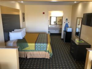 a hotel room with a bed and a flat screen tv at Homegate Inn & Suites West Memphis in West Memphis