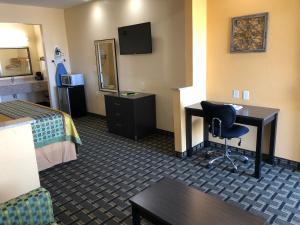 a hotel room with a bedroom with a desk and a bed at Homegate Inn & Suites West Memphis in West Memphis