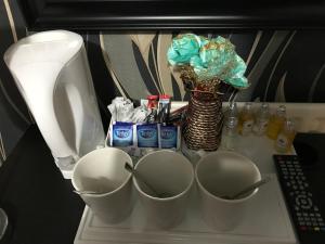 a shelf with three measuring cups and a toilet at Pacific Inn London Heathrow in Southall