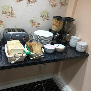 a counter with plates and bowls on a table at Pacific Inn London Heathrow in Southall +25 photos