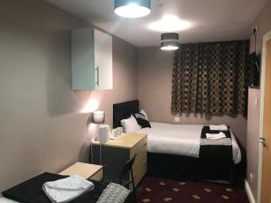 a hotel room with a bed and a desk and a room at Pacific Inn London Heathrow in Southall