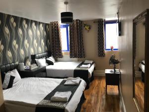 a hotel room with two beds and a table at Pacific Inn London Heathrow in Southall