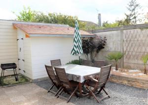 d'une terrasse avec une table et des chaises dans l'arrière-cour. dans l'établissement Villa des sables avec 1 studio pour 2 personnes pouvant être complété par une chambre avec sa salle de bain et WC si 4 personnes, à Le Home Varaville