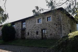a large stone building with windows and grass at Casa de Aldea Casina de Rubio in Linares