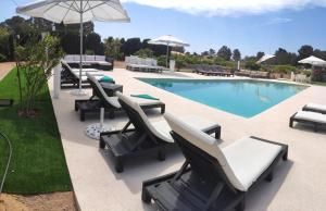 a swimming pool with lounge chairs and an umbrella at MAR Y MONTAÑA FORMENTERA in Sant Francesc Xavier
