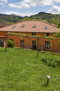 pomarańczowy dom z zielonym trawnikiem przed nim w obiekcie Casa Rural Enkartada w mieście Sopuerta