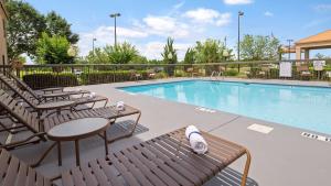 una piscina con sillas, mesa y mesa en SureStay Plus Hotel by Best Western Roanoke Rapids I-95, en Roanoke Rapids